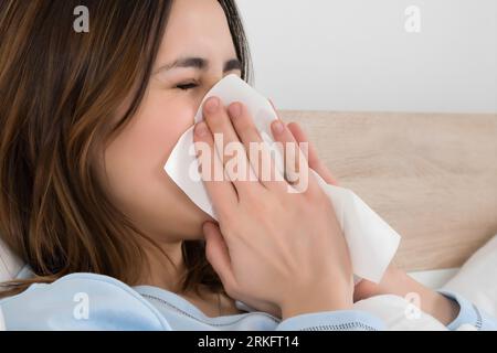 Jeune femme infectée par soufflage froid son nez dans un mouchoir Banque D'Images