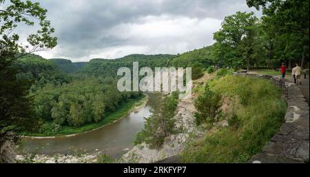 Un groupe de personnes prenant une promenade tranquille le long d'un sentier sinueux le long d'une rivière Banque D'Images