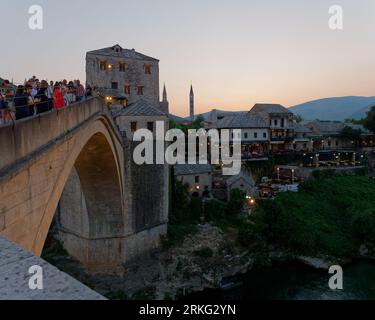 Les touristes apprécient la vue depuis Stari Most (vieux pont) sur la rivière Neretva lors d'une soirée d'été à Mostar, Bosnie-Herzégovine, le 20 août 2023. Banque D'Images