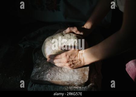 Une femme vêtue de vêtements ukrainiens traditionnels pétrit de la pâte à pain. Banque D'Images