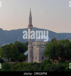 Les touristes apprécient la vue de la mosquée Koski Mehmed Pacha à Mostar un soir d'été avec la montagne derrière, Bosnie-Herzégovine, 22 août 2023. Banque D'Images