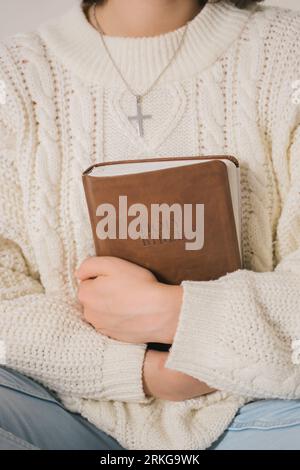 Une jeune femme en chandail blanc tenant la Sainte Bible Banque D'Images