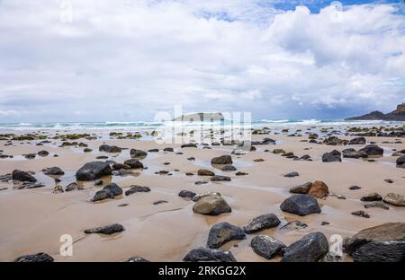Un paysage de plage pittoresque avec un rivage serein avec des rochers dispersés le long du sable doré Banque D'Images
