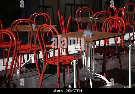 Patio de café local avec chaises de bistro rouge vif sur la via Bordonaro à Cefalù Sicile, Italie. Banque D'Images