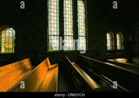 Une belle vieille église éclairée par le soleil qui coule à travers les vitraux, créant une atmosphère magnifique et paisible Banque D'Images