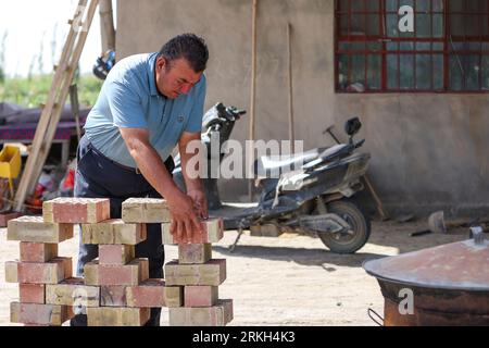 (230825) -- YULI, 25 août 2023 (Xinhua) -- Arkin Reyim construit un mur de fleurs dans la cour de son champ de coton dans le village de Bax Mali du comté de Yuli, dans la région autonome ouïgour du Xinjiang, au nord-ouest de la Chine, le 17 août 2023. Août est le moment où Arkin Reyim prend soin des boules de coton dans sa ferme de coton de plus de 300 mu (20 hectares) dans le village de Bax Mali dans le comté de Yuli. Après les semis de printemps cette année, une chute soudaine de la température en mai a presque détruit sa ferme. Grâce à ses expériences, Arkin Reyim a semé à nouveau dans le temps et a rattrapé la perte. Outre le champ de coton, Arkin Reyim plante également Banque D'Images