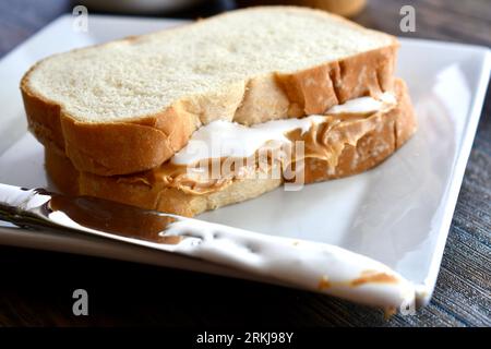 Un sandwich Fluffernutter à base de beurre de cacahuète et de crème de guimauve sur une assiette blanche Banque D'Images