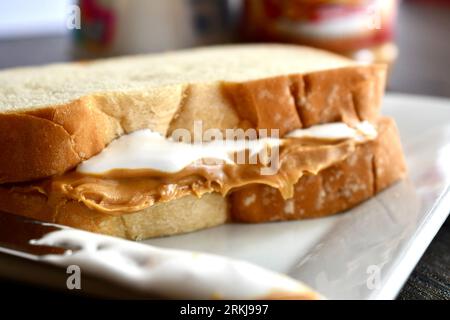 Un sandwich Fluffernutter à base de beurre de cacahuète et de crème de guimauve sur une assiette blanche Banque D'Images