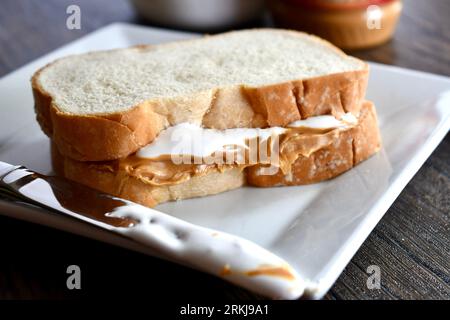 Un sandwich Fluffernutter à base de beurre de cacahuète et de crème de guimauve sur une assiette blanche Banque D'Images