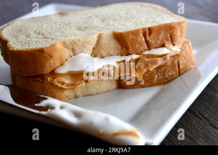 Un sandwich Fluffernutter à base de beurre de cacahuète et de crème de guimauve sur une assiette blanche Banque D'Images