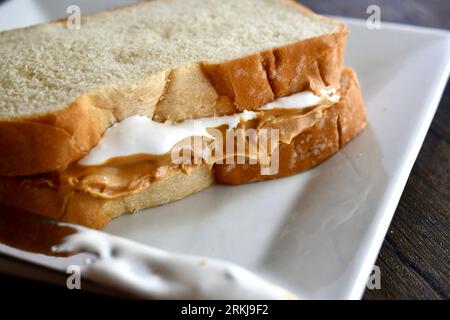 Un sandwich Fluffernutter à base de beurre de cacahuète et de crème de guimauve sur une assiette blanche Banque D'Images