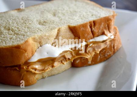 Un sandwich Fluffernutter à base de beurre de cacahuète et de crème de guimauve sur une assiette blanche Banque D'Images