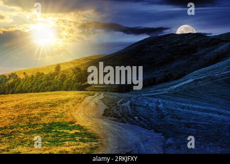 paysage de montagne au début de l'automne avec chemin à travers la colline avec soleil et lune au crépuscule. concept de changement de jour et de nuit. mystérieux countryside Banque D'Images