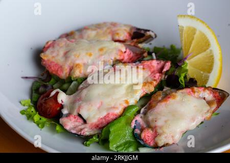 moules cuites au four avec du caviar masago et du fromage sur une assiette blanche avec du citron Banque D'Images