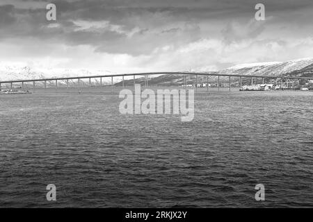 Photo en noir et blanc du pont Tromsø (Tromsøbrua) de 1036 mètres de long enjambe le détroit de Tromsøysundet au nord du centre-ville de Tromso. Norvège. Banque D'Images