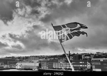 Photo en noir et blanc du drapeau norvégien (enseigne norvégienne) volant de la poupe du MS NORDNORGE amarré à Tromsø, Norvège. 5 mai 2023 Banque D'Images