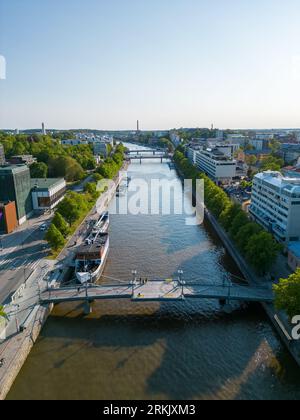 Une rivière tranquille serpente à travers un paysage urbain animé dans la lumière chaude de l'après-midi : Turku Banque D'Images