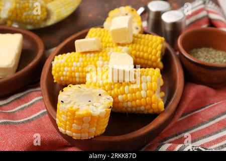 Assiette d'épis de maïs bouillis avec du beurre sur fond sombre Banque D'Images