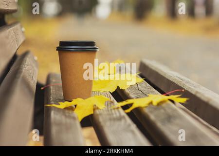 tasse à café et feuilles jaunes sur un banc dans un parc d'automne. concept de saison d'automne Banque D'Images