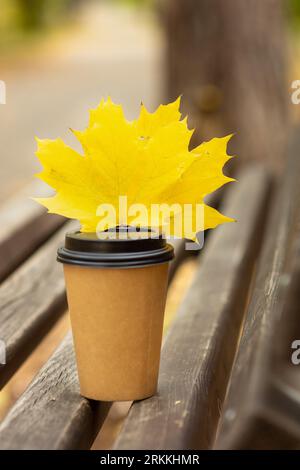 tasse à café et feuilles jaunes sur un banc dans un parc d'automne. concept de saison d'automne Banque D'Images