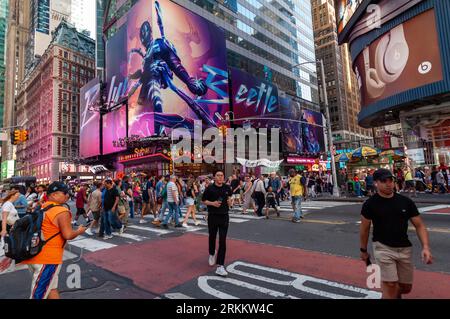 Des hordes de gens traversent West 42nd Street sous la publicité pour Warner Bros. Film « Blue Beetle » à Times Square à New York le vendredi 18 août 2023. Au cours de son week-end de sortie, "Blue Beetle" a supplanté "Barbie" comme le meilleur film de récolte avec un montant estimé à 25,4 millions de dollars. . (© Richard B. Levine) Banque D'Images