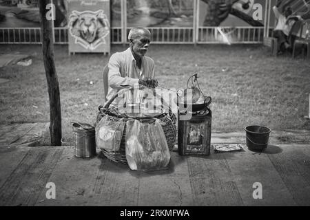 Old Man frit Samosa (nourriture indienne) dans de très petites installations de fabrication de nourriture dans les rues de l'Inde. Banque D'Images