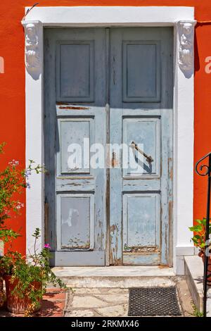 Porte d'entrée traditionnelle en bois avec portes doubles, un linteau en pierre et un seuil, et un mur rouge vif, à Parga, Preveza, Grèce Banque D'Images