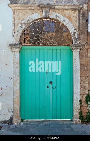 Vieille porte traditionnelle en bois de couleur vert clair dans une vieille maison avec arc en pierre et linteau de fer, dans la ville de Preveza, région d'Epire, Grèce, Europe Banque D'Images