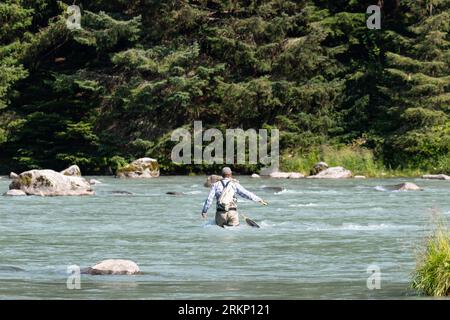 Pêcheur à la mouche pêchant au milieu de la rivière un jour d'été. Banque D'Images