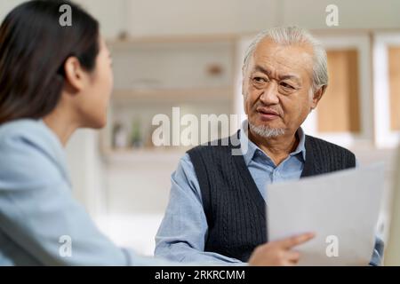 senior asian man appears to be confused by and suspicious at a sales person selling financial product Stock Photo