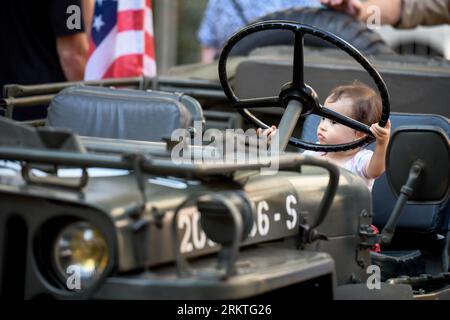 Avignon, France. 25 août 2023. Un bébé est vu derrière le volant d'une des voitures d'exposition de la Seconde Guerre mondiale. À l'occasion du 79e anniversaire de la libération d'Avignon en France pendant la Seconde Guerre mondiale, une exposition présentant une gamme de véhicules militaires et civils se déploie devant la mairie. Crédit : SOPA Images Limited/Alamy Live News Banque D'Images