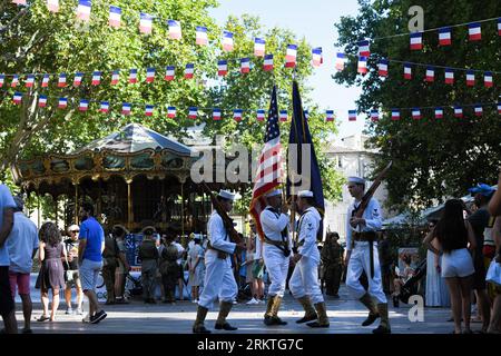 Avignon, France. 25 août 2023. Des soldats des États-Unis défilent avec le drapeau américain sur la place de la ville. À l'occasion du 79e anniversaire de la libération d'Avignon en France pendant la Seconde Guerre mondiale, une exposition présentant une gamme de véhicules militaires et civils se déploie devant la mairie. Crédit : SOPA Images Limited/Alamy Live News Banque D'Images