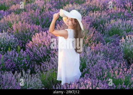 fille joyeuse aux fleurs de lavande dans le jardin. Jeune fille en robe blanche marchant à travers les fleurs de lavande. belle fille posant dans les fleurs de lavande. beaut Banque D'Images