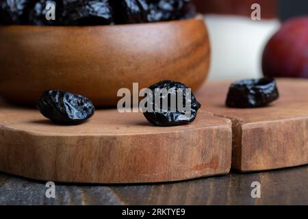 Pile noire de pruneaux d'un grand nombre de prunes mûres, une pile de pruneaux sur une table en bois dans la cuisine gros plan Banque D'Images