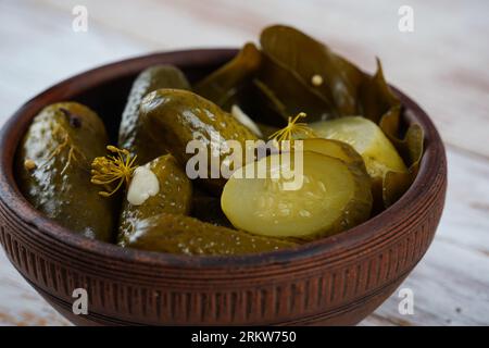 Concombres marinés dans un bol sur une table rustique en bois avec de l'ail. Cornichons de concombres marinés Banque D'Images