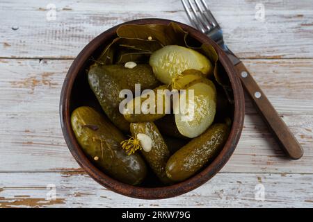 Concombres marinés dans un bol sur une table rustique en bois avec de l'ail. Cornichons de concombres marinés Banque D'Images