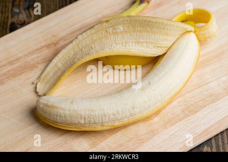 Banane jaune mûre pelée, coupe de banane pour la cuisson du dessert est sur la planche Banque D'Images