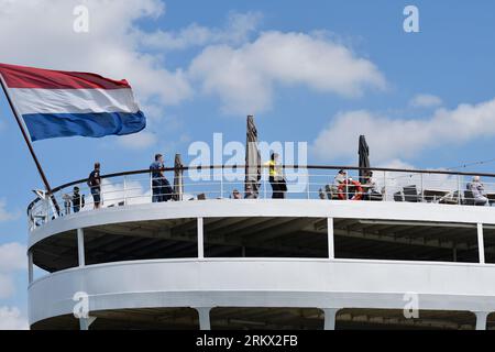 Visiteurs sur la terrasse du ss Rotterdam, ancien navire à passagers Holland America Line. Le tricolore hollandais flotte dans le vent Banque D'Images