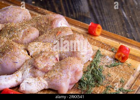 Viande de poulet fraîchement lavée et pelée, pattes de poulet salées et épices prêtes à cuire Banque D'Images