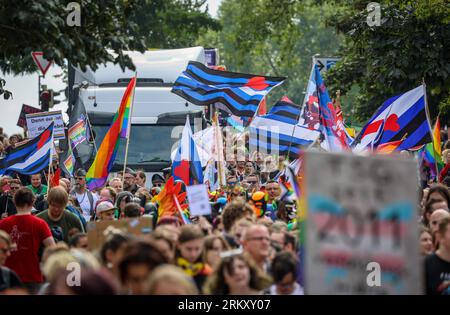 Brême, Allemagne. 26 août 2023. Les participants du Christopher Street Day (CSD) marchent le long du Sielwall à Brême avec un drapeau et des panneaux. Pour le cortège de manifestation à travers la ville hanséatique, la police attendait 10 000 à 12 000 personnes. Crédit : Focke Strangmann/dpa/Alamy Live News Banque D'Images