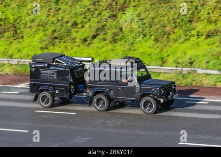 Remorque de camping avec panneaux solaires remorquée par 1986 British Landrover. LR 90 4C Reg Di Black LCV Hardtop Van Diesel 2495 cc ; voyageant à grande vitesse sur l'autoroute M6 dans le Grand Manchester, Royaume-Uni Banque D'Images