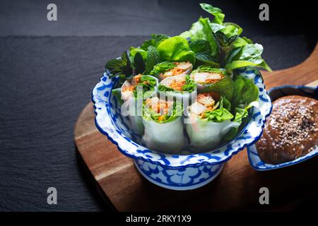 Concept d'aliments sains rouleaux d'été tofu végétaliens faits maison ou rouleau de printemps avec sauce de trempage d'arachide sur fond noir avec espace copt Banque D'Images