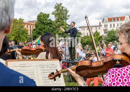 26 août 2023, Brandenburg, Cottbus : lors d'un concert à l'occasion de l'ouverture du Théâtre d'État de Cottbus pour la nouvelle saison, des musiciens amateurs, dirigés par le directeur musical général Alexander Merzyn (M), divertissent les visiteurs présents. 'Ensemble. Ici.' C'est la devise du Théâtre d'État de Cottbus pour la saison 2023/24, que le théâtre à quatre orateurs de Brandebourg célèbre ce week-end avec les citoyens. Un total de 19 premières dans les divisions théâtre, théâtre musical et ballet, huit concerts philharmoniques et de nombreux événements dans le «format spécial» et «spécial» Banque D'Images