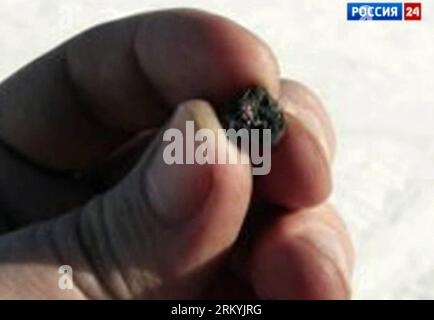 Bildnummer : 59234122 Datum : 18.02.2013 Copyright : imago/Xinhua (130218) -- CHELYABINSK, 18 février 2013 (Xinhua) -- une capture d'écran de télévision prise sur la chaîne 24 de la télévision d'État russe montre un chercheur scientifique tenant un fragment de météore trouvé dans la région du lac Chebarkul près de Chelyabinsk, à environ 1500 kilomètres à l'est de Moscou, Russie, le 18 février 2013. Les scientifiques ont trouvé des fragments d un météore qui a explosé au-dessus de l Oural central de la Russie et a déclenché une onde de choc qui a blessé des centaines de personnes et brisé des dizaines de fenêtres, ont déclaré lundi des experts. (Xinhua) (dtf) FRAGMENTS RUSSIE-CHELYABINSK-MÉTÉOR Banque D'Images