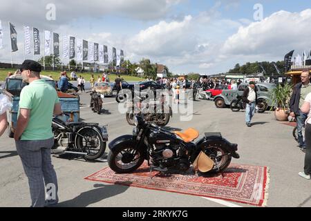 Schleiz, Allemagne. 26 août 2023. Les visiteurs traversent la zone d'exposition à l'ouverture du Motorwelt 'Schleizer Dreieck'. Le Schleizer Dreieck est le plus ancien circuit routier d'Allemagne et est encore aujourd'hui le lieu de courses dans les sports automobiles. Le musée sera consacré à l'histoire centenaire de la piste de course. Crédit : Bodo Schackow/dpa/Alamy Live News Banque D'Images