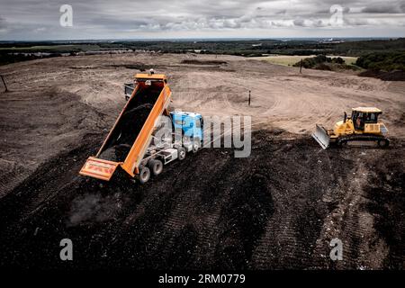 Tombereau déchargeant les déchets dans une grande décharge de déchets avec hayon relevé et bulldozer en attente de gestion de la pile avec espace de copie Banque D'Images