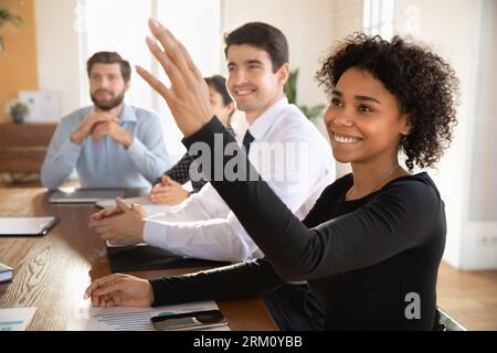 Motivated african American woman raise hand at office meeting Stock Photo