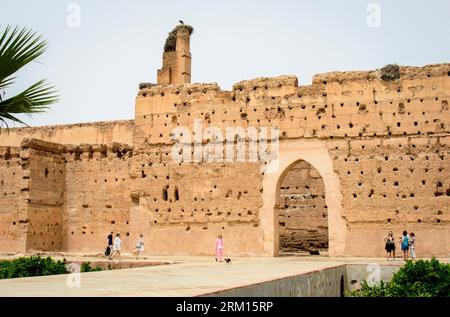 Marrakech, Maroc, 8 avril 2023. Touristes debout près d'un ancien mur avec une porte en arc à l'intérieur du palais Badi de Marrakech. Banque D'Images