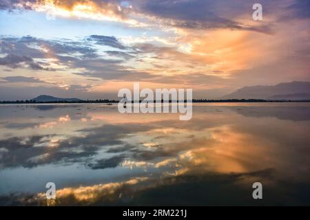 Srinagar, Inde. 26 août 2023. Un homme rame son bateau à travers le lac Dal au coucher du soleil à Srinagar, la capitale estivale du Jammu-et-Cachemire. (Photo Saqib Majeed/SOPA Images/Sipa USA) crédit : SIPA USA/Alamy Live News Banque D'Images