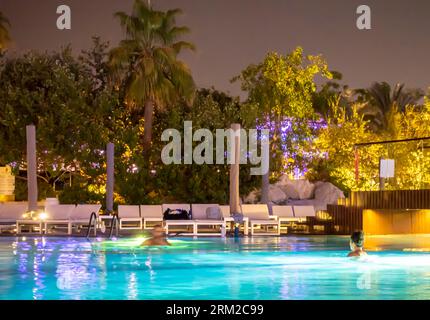 Les touristes nagent dans la piscine de la station balnéaire dans la nuit, Bahreïn Banque D'Images